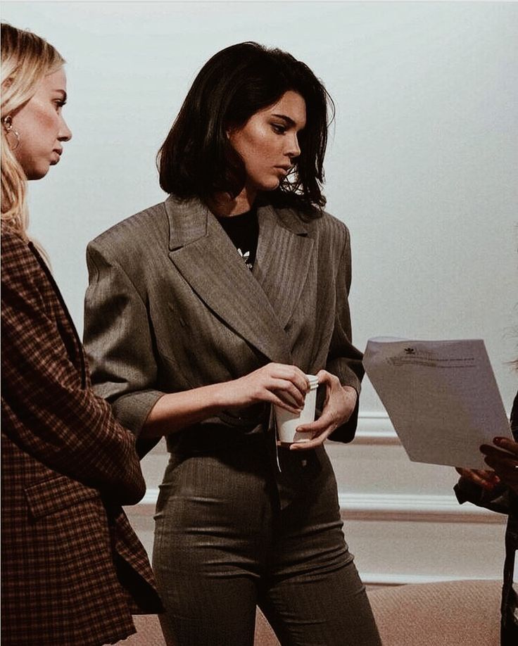 two women standing next to each other in front of a projector screen and talking