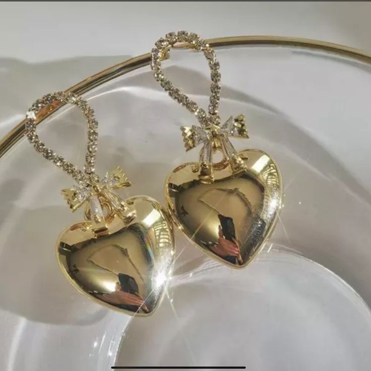 This Is A Very Beautiful Pair Of Gold Plated Metal Heart Dangle Earrings . They Have A Bow Made Of Baguette Cz Stones And The Top Of Earrings Have Pave Cz Stones . The Length Is 3.8 Inches And The Hearts Are A Puffed Heart Design . Metal Crystal Earrings For Valentine's Day Gift, Gold Heart-shaped Earrings With Rhinestones, Gold Rhinestone Heart Earrings, Glamorous Dangle Earrings For Valentine's Day, Glamorous Heart Earrings With Rhinestones As Gift, Elegant Metal Heart Cut Earrings, Elegant Metal Heart Earrings For Valentine's Day, Elegant Metal Crystal Earrings For Valentine's Day, Glamorous Rhinestone Heart Earrings As Gift