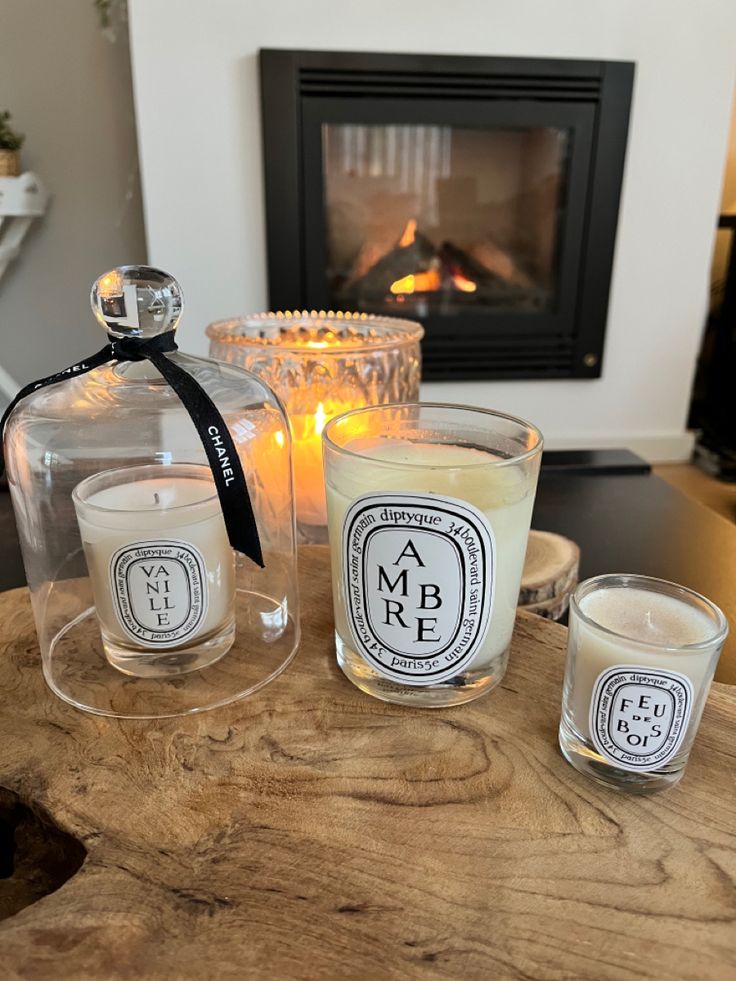 three candles sitting on top of a wooden table next to a glass jar with a candle in it