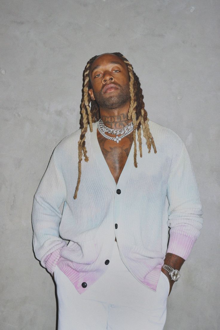 a man with dreadlocks standing in front of a wall