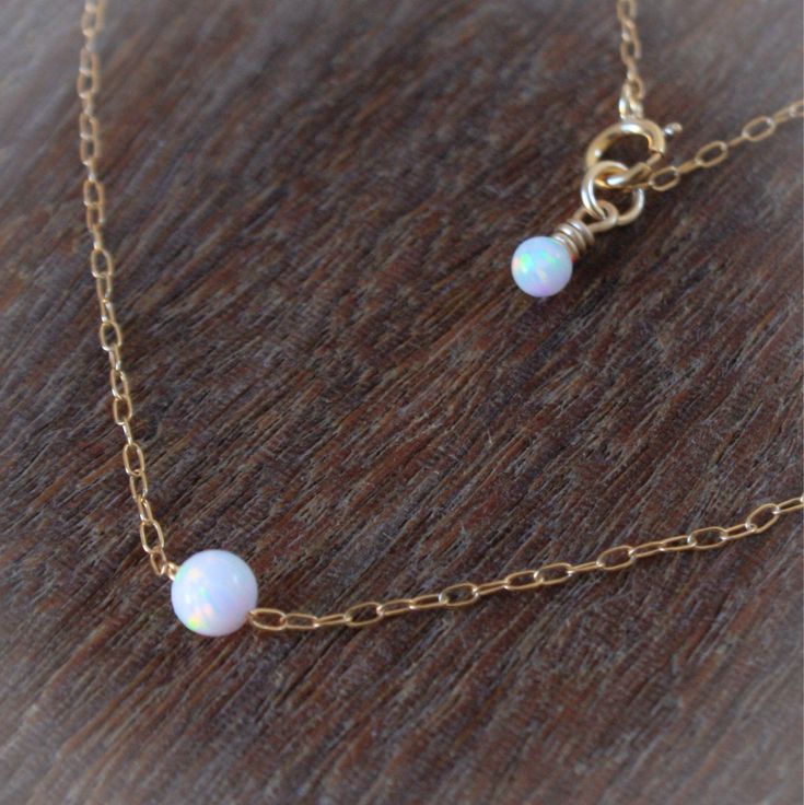 Simple. Chic. Minimalist™ A perfectly dainty brilliant synthetic white opal ball floating on a delicate feminine sterling silver chain, with a tiny White opal wire wrapped with sterling Silver wire added to the clasp for an extra classy look. Opal ball measures 4mm. It has a touch of white and turquoise colors with glints of pink. Also available with 14K gold filled / 14K rose gold filled chain. 〰 This white opal color is unique and exclusive to miniLALI's shop. You will not find this color anyw White Opal Birthstone Jewelry, Delicate White Opal Jewelry, Dainty Opal Round Pendant Necklace, Dainty Round Opal Necklace, Dainty White Opal Jewelry, Simple White Round Beads Jewelry, Simple White Round Bead Jewelry, Simple White Round Beaded Jewelry, White Opal Necklace With Delicate Chain