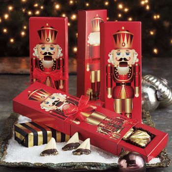 three red boxes filled with chocolates and nutcrackers on top of snow