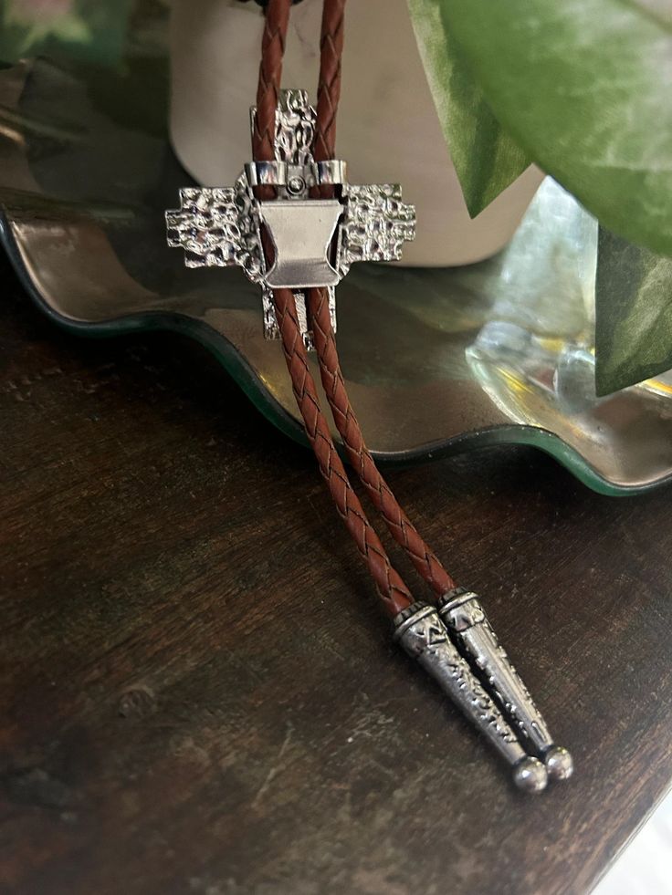 This awesome bolo tie has a southwestern cross design and agate stone centerpiece. Our bolos pair nicely with many of our belt buckles! They make wonderful gifts. The western bolo tie rope length is 100cm (39") and the pendant is 1 3/4'' wide Southwestern Lariat Bolo Tie For Rodeo, Western Lariat Bolo Tie With Adjustable Length, Western Style Lariat Bolo Tie With Adjustable Length, Western Jewelry With Adjustable Length For Rodeo, Southwestern Lariat Bolo Ties For Ranch, Southwestern Bolo Ties With Concho, Concho Lariat Bolo Ties For Rodeo, Rodeo Lariat Bolo Tie With Adjustable Length, Adjustable Lariat Bolo Ties For Rodeo