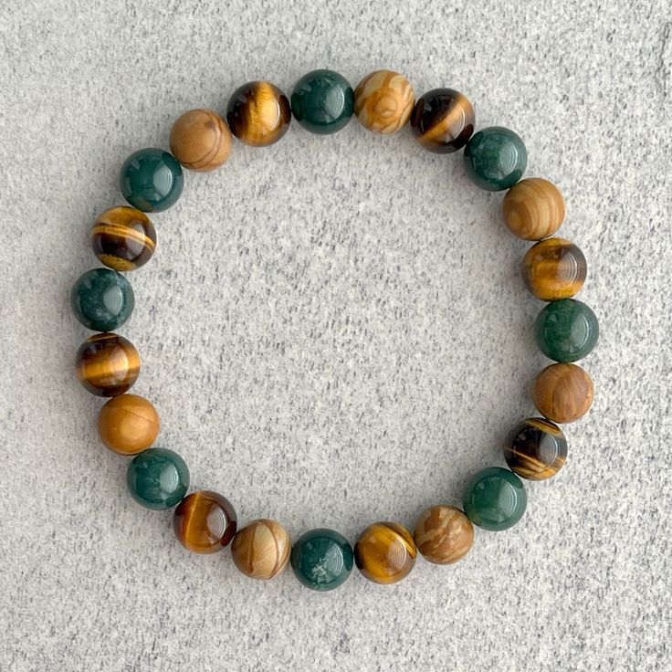 ~ 8mm moss agate beads ~ 8mm yellow tiger eye beads ~ 8mm wood jasper beads ~ Stretchy cord; simply slide bracelet on and off wrist ~ Comes packaged in a re-usable microfibre pouch To ensure the perfect fit, please use the bracelet sizing instructions found in the photo gallery. Cheap Wooden Bead Bracelets For Gifts, Cheap Wooden Beads Bracelet, Cheap Agate Beaded Bracelets, Yellow Beaded Bracelets, Jasper Bead Bracelet, Stretchy Beaded Bracelet, Slide Bracelet, Jasper Bracelet, Beads Bracelet Design