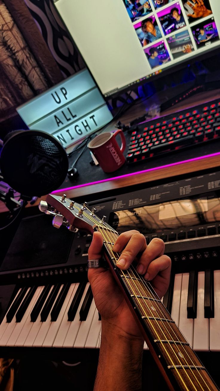 a person playing an electric guitar in front of a keyboard and monitor with the words up all night written on it