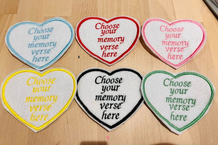 four heart shaped embroidered patches with different words on them, all in various colors and sizes