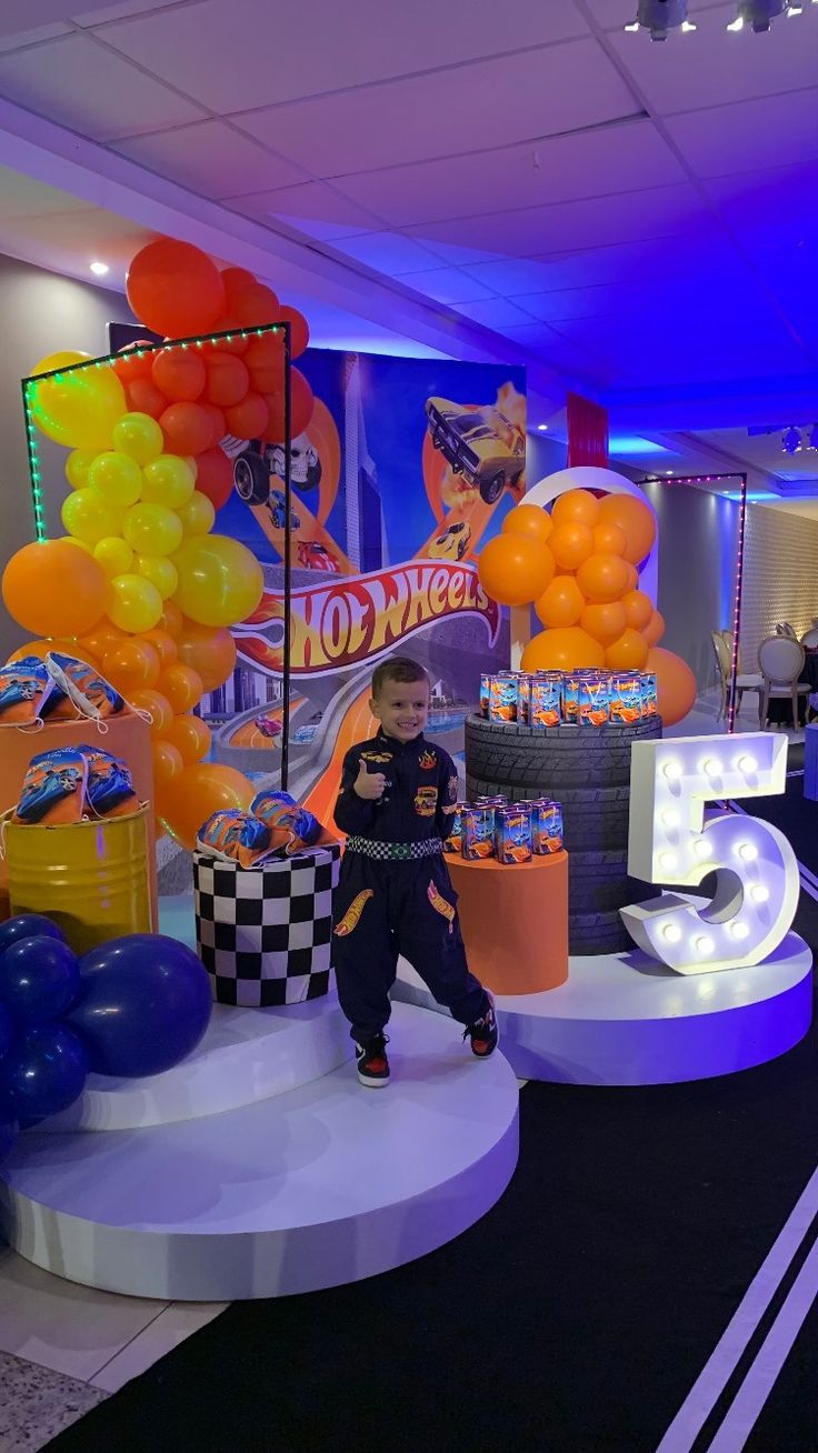 a young boy sitting on top of a table in front of balloons