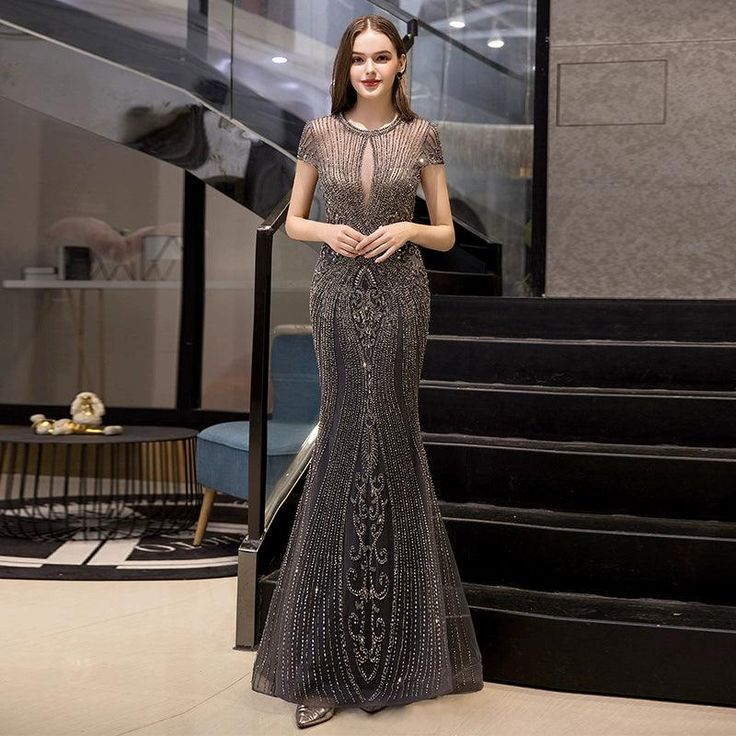 a woman standing in front of some stairs wearing a dress with beading on it