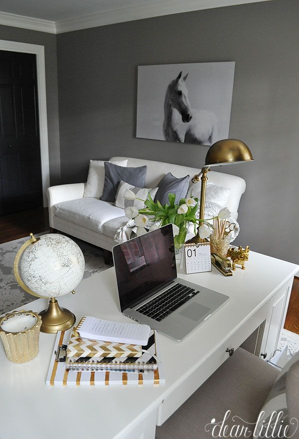 a laptop computer sitting on top of a white desk in front of a couch and chair