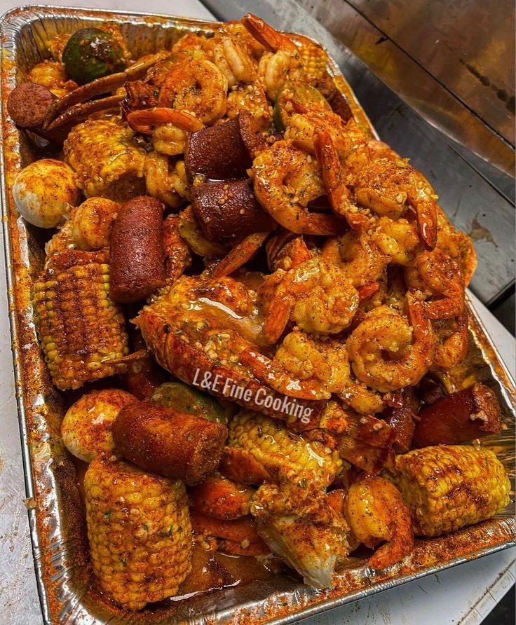 a tray filled with cooked shrimp and corn on the cob