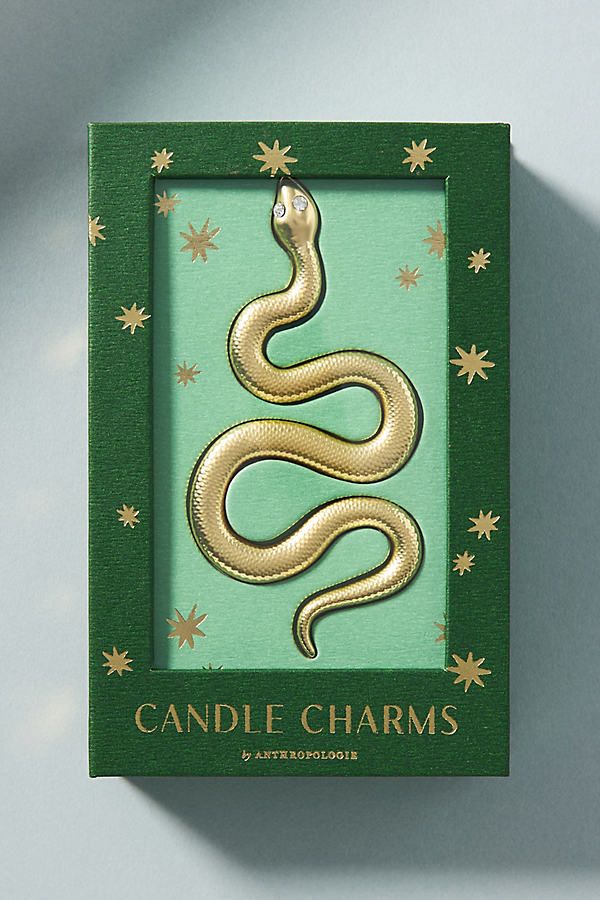 a green box with a gold snake in it's center and the words candle charms