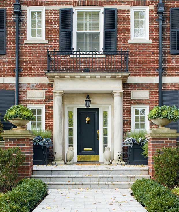 a brick building with black shutters and white trim on the front door is shown