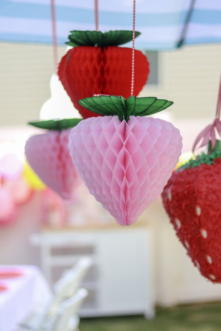 three paper strawberries hanging from strings in the shape of heart and strawberrys with leaves on them