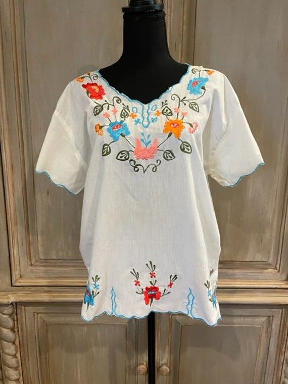 Cute Mexican embroidered top! Vibrant  flowers in orange, red and blue on a dark green vine surround the neckline and continue down the bodice. The same design can be found on the sleeves and edging the  bottom. The same areas have a turquoise embroidered edge. The size is estimated to be a ladies M.  The garment is in perfect condition, showing no signs of wear.  I do not make exchanges or accept returns.  Don't hesitate to contact me with questions! Multicolor Floral Embroidered V-neck Top, Multicolor V-neck Top With Floral Embroidery, Traditional V-neck Blouse With Embroidered Hem, Fitted Top With Multicolor Floral Embroidery, Festival Tops With Embroidered Hem, Multicolor Embroidered Floral Print V-neck Top, Casual Multicolor Tops With Embroidered Sleeves, Peasant V-neck Top With Floral Embroidery, Fitted V-neck Tops With Embroidered Neckline