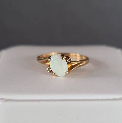 a gold ring with a white opal stone on the front, and an open band around it