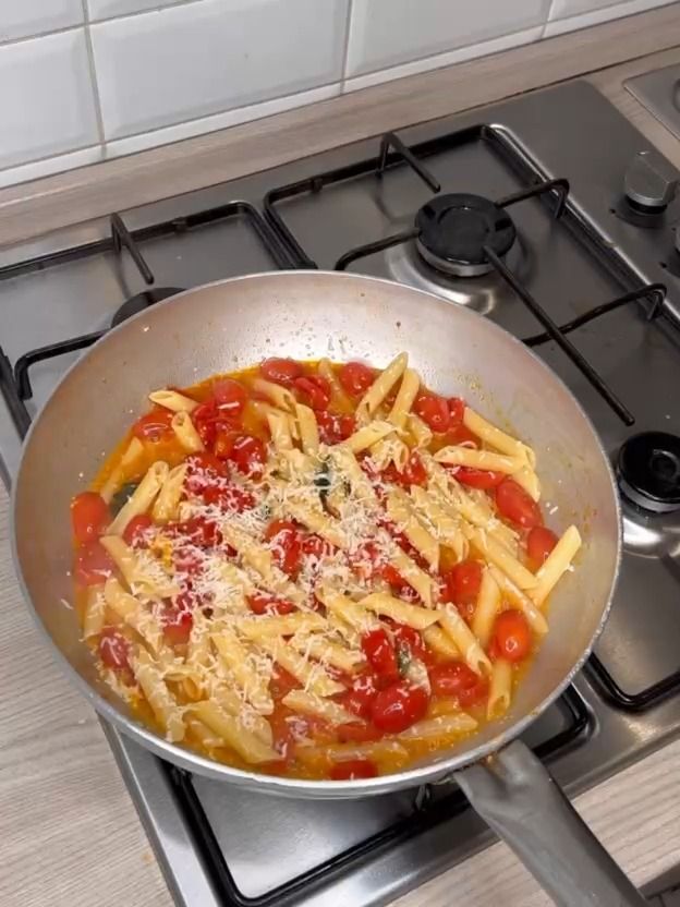 a pan filled with pasta and tomato sauce on top of a stovetop burner