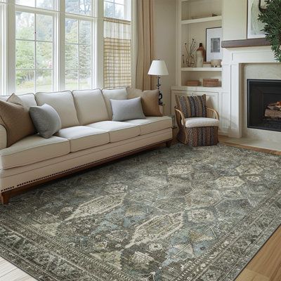 a living room filled with furniture and a large rug on top of a hard wood floor