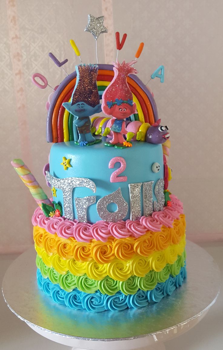 there is a birthday cake decorated with fondant and rainbows on the top tier