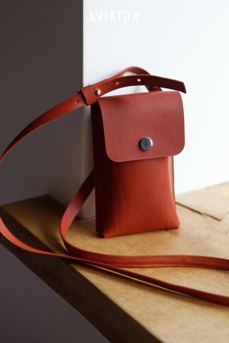 a brown leather bag sitting on top of a wooden table next to a white wall