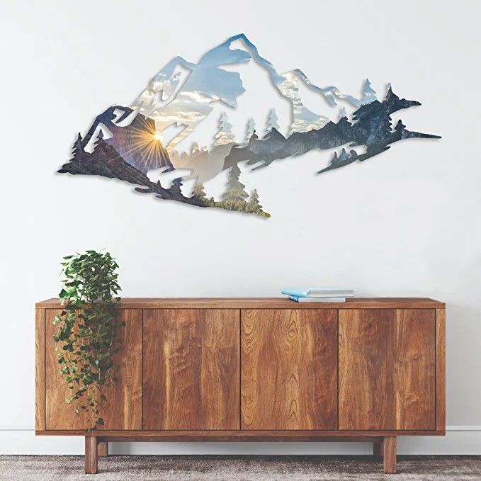 a wooden cabinet sitting in front of a wall with mountains on the top and trees below