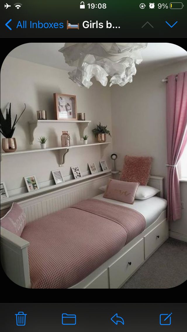 a bedroom with pink and white decor on the walls, shelving above the bed