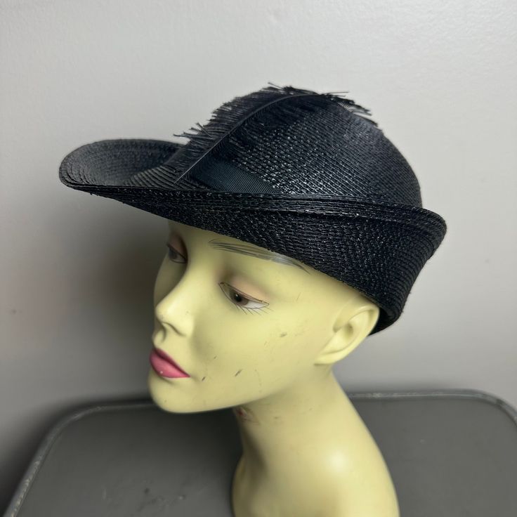 This unique vintage hat from the 1950s is a must-have for any fashion enthusiast. The black straw material is complemented by a single long feather and a ribbon. The unique brim gives it a stylish and elegant look. The hat is perfect for any occasion and will surely make a statement wherever you go. It is an original piece and is not reproduced, adding to its value and appeal. The hat has a monochrome look that will match any outfit. It is a great addition to any vintage accessories collection a Vintage Black Mini Hats For Summer, Vintage Black Mini Hat For Spring, Black Wide Brim Retro Hat, Vintage Black Hat For Spring, Vintage Black Fedora Hat, Vintage Black Wide Brim Hat, Black Summer Hat With Feather Trim, Black Summer Hats With Feather Trim, Summer Black Hats With Feather Trim