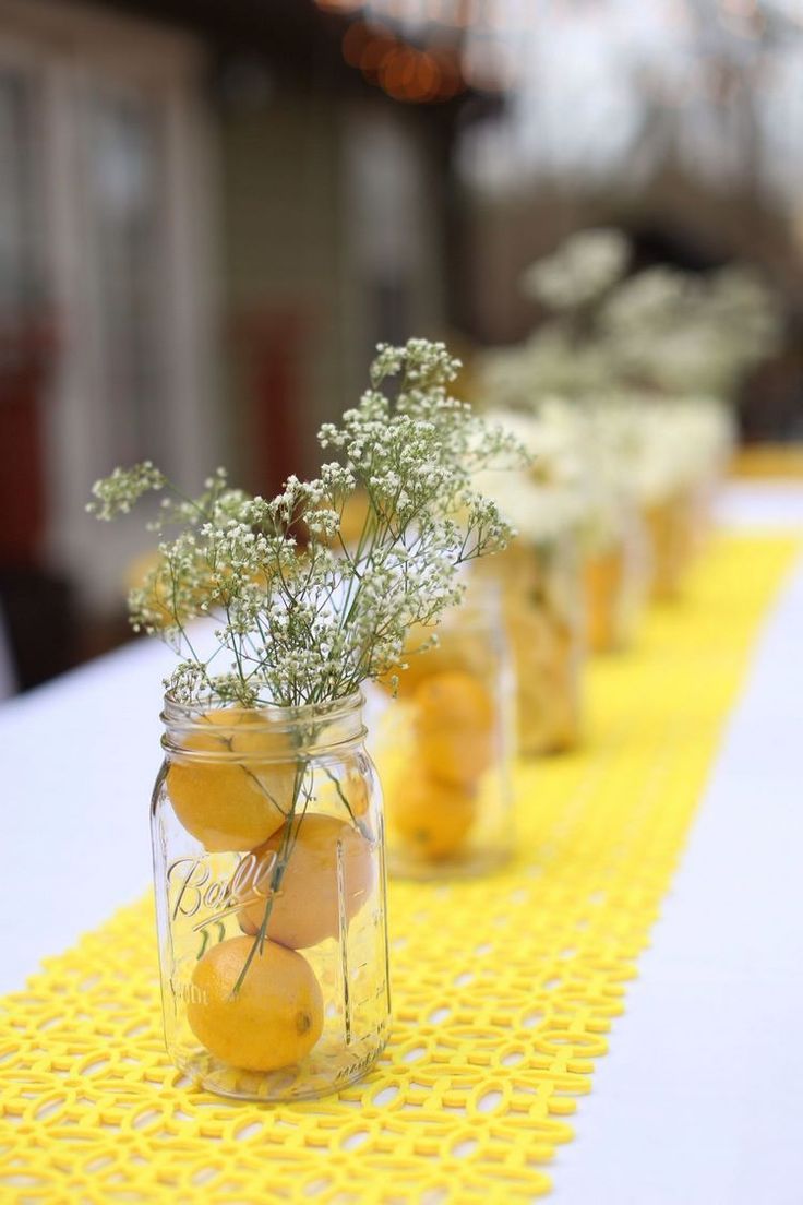 small mason jars filled with lemons and baby's breath are lined up on a table