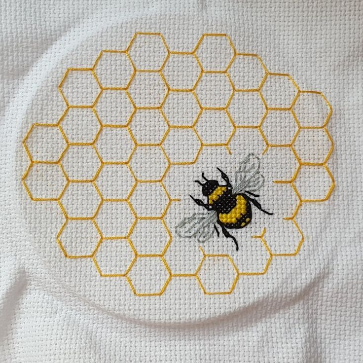 a close up of a piece of cloth with a cross stitch bee on the center