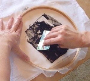 two hands on a plate that is being decorated with black and white squares, while another hand holds a piece of paper in front of it