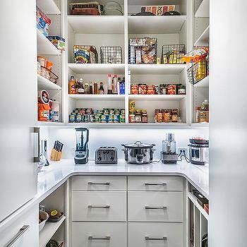 an organized pantry with white cabinets and drawers