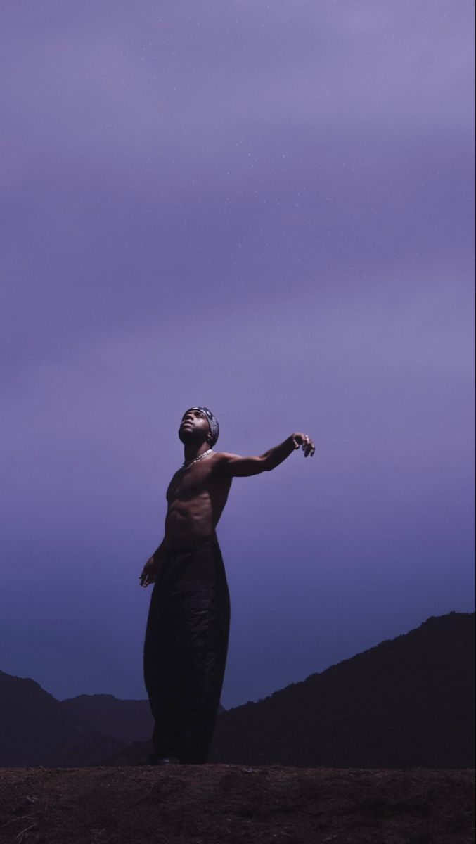 a man standing on top of a hill under a purple sky