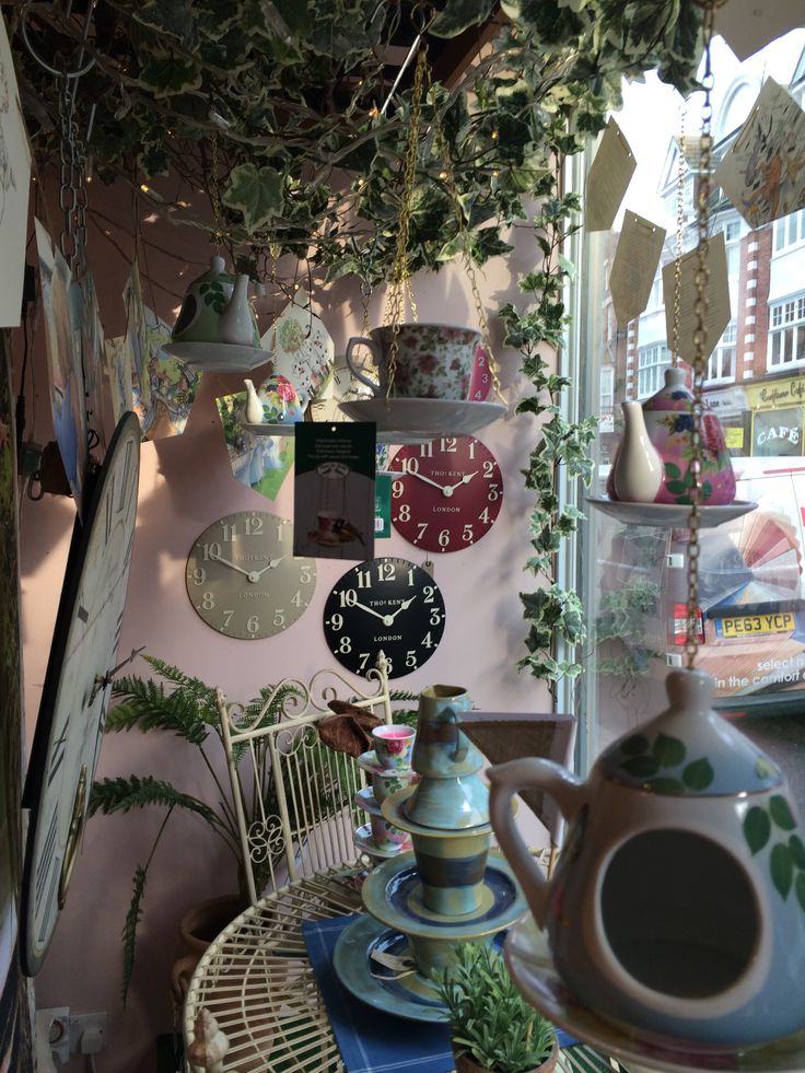 there are many clocks hanging on the wall in this room, and one is decorated with plants