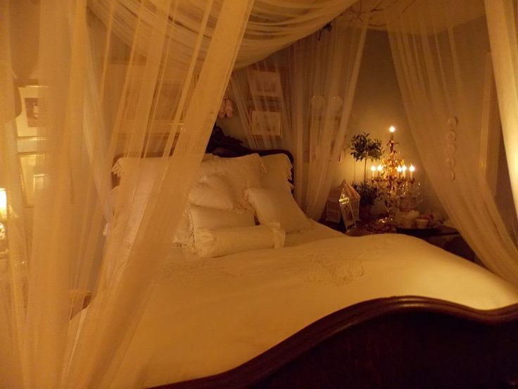 a canopy bed with white sheets and pillows