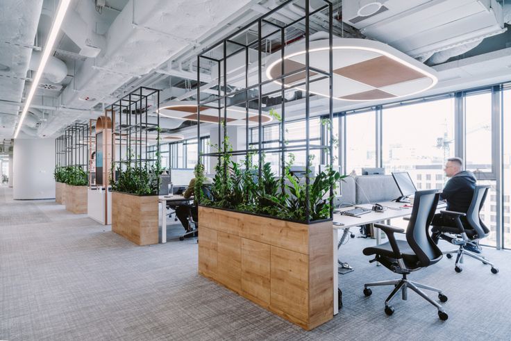 an office with plants on the desks and people working in the chairs around them