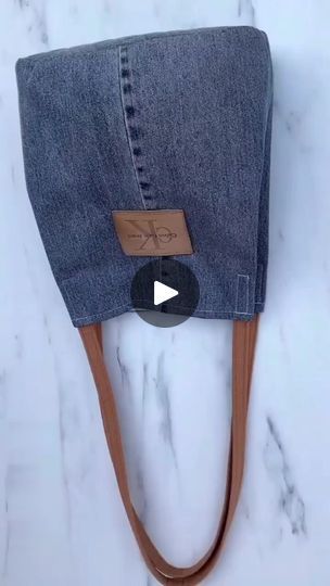 a pair of jeans hanging from a hook on a marble counter with a leather cord