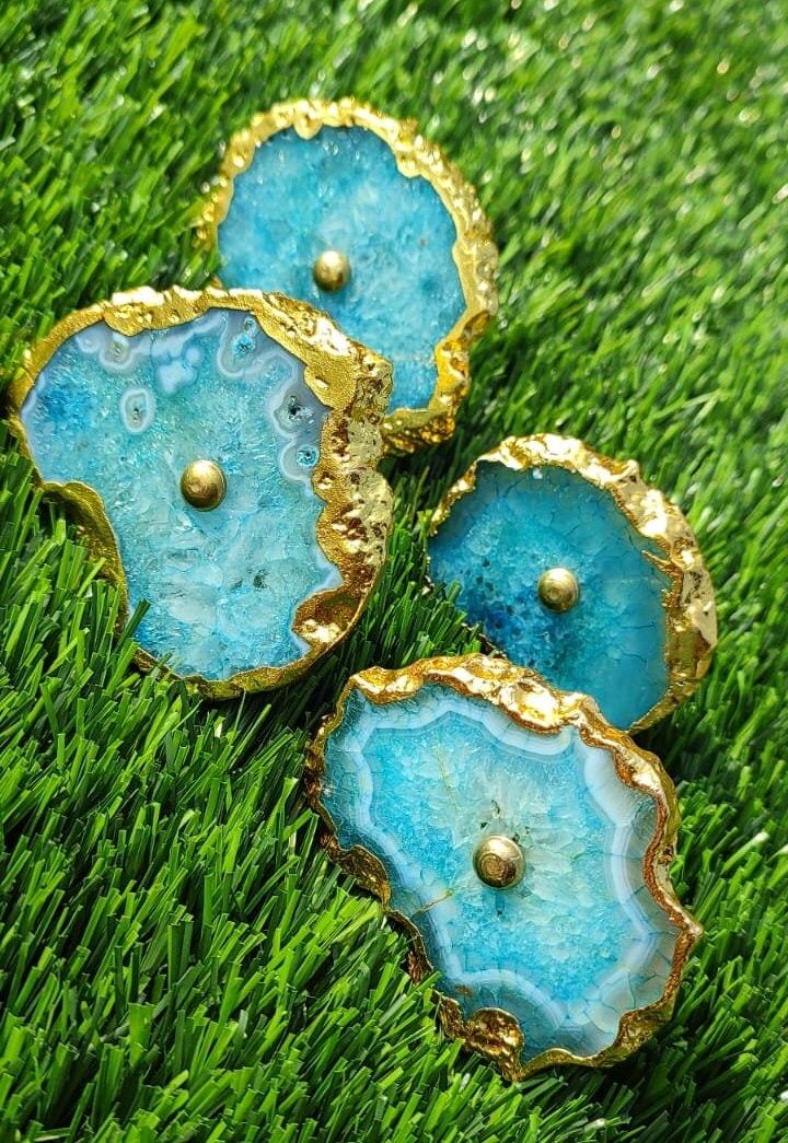 three pieces of blue agate with gold accents sitting in the grass on top of green grass