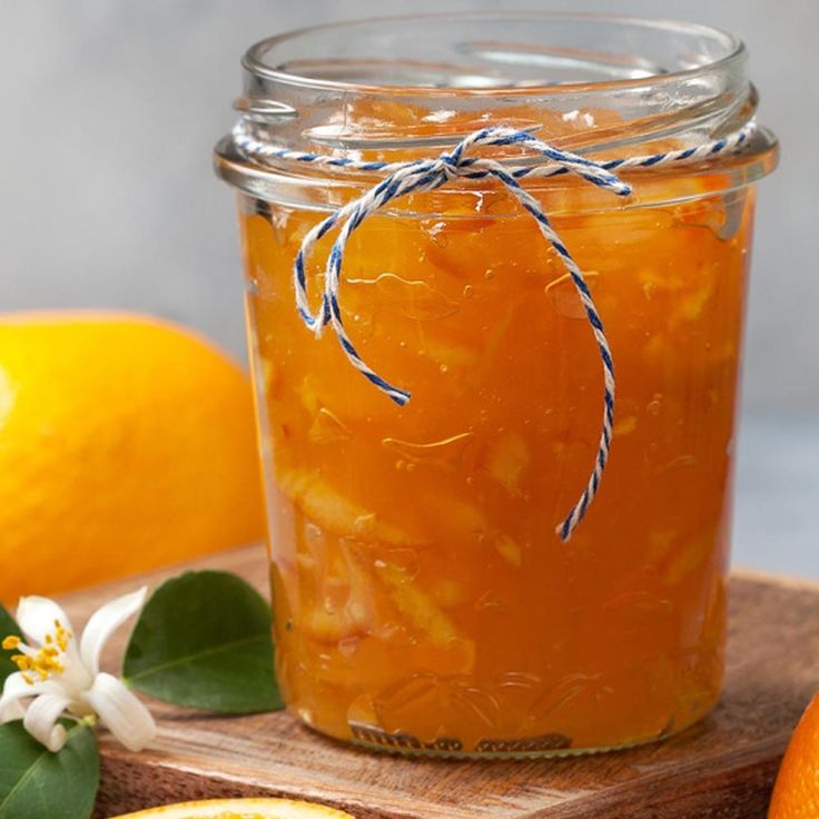 a jar filled with liquid sitting on top of a cutting board next to sliced oranges