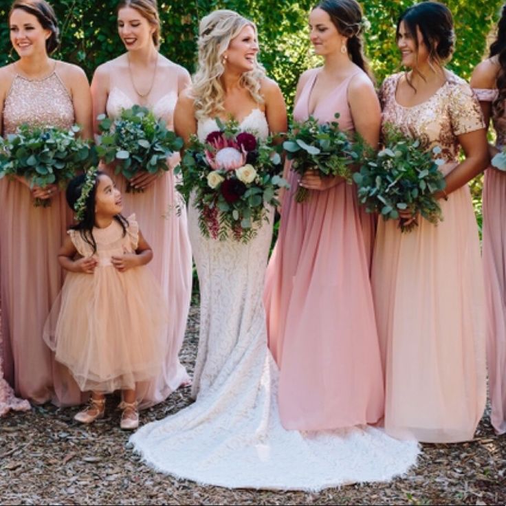 a group of women standing next to each other wearing dresses and holding bouquets in their hands