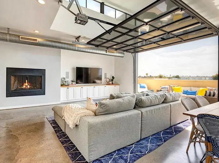 a living room with a couch, table and television on the wall next to an open fire place