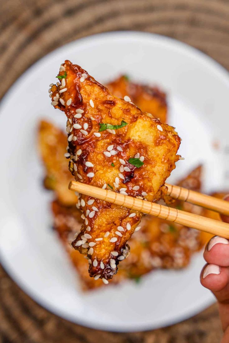 a person holding chopsticks in their hand with some food on it and the words easy dinner crispy sticky tofu