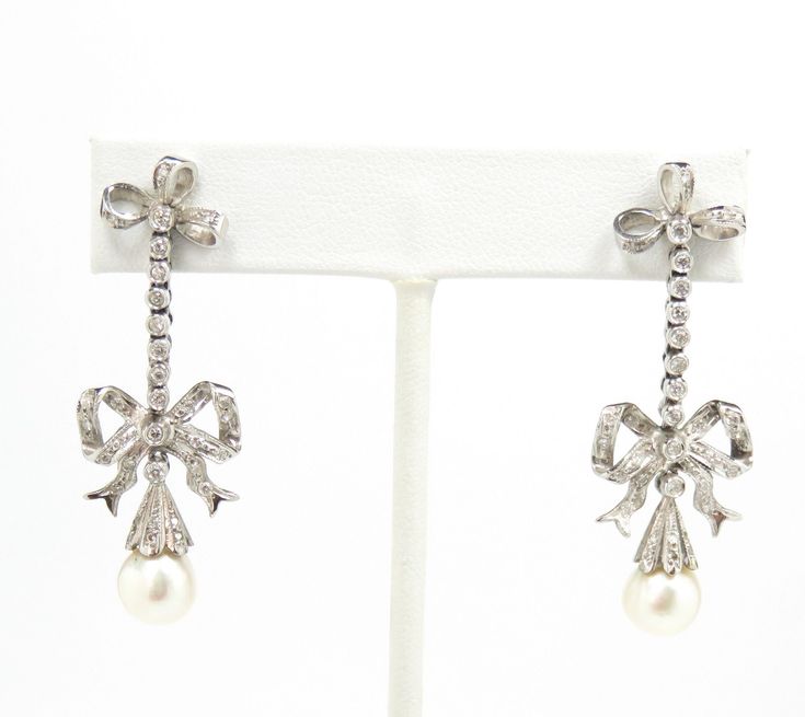 "14k white gold .40 carats diamonds G in color 2 8mm pearls 2\" long condition: excellent Gorgeous pair of French earrings, crafted of 14 karat white gold and set with white pearls and natural diamonds.  The earrings are dramatic, measuring just under 2\" long, and feature an Edwardian design, with a stylized bow motif at the piercing and just above the drop.  A row of diamonds lines the upper dangle, and  diamonds embellish a large bow just above the bead cap.  The bead cap, which is also studd Elegant Platinum Pearl Earrings For Wedding, Wedding Silver Platinum Pearl Earrings, Silver Platinum Pearl Earrings For Wedding, White Gold Pearl Earrings With 17 Jewels For Wedding, Fine Jewelry Platinum Pearl Earrings For Wedding, Platinum Pearl Earrings For Wedding, Edwardian Design, Diamond And Pearl Earrings, French Earrings