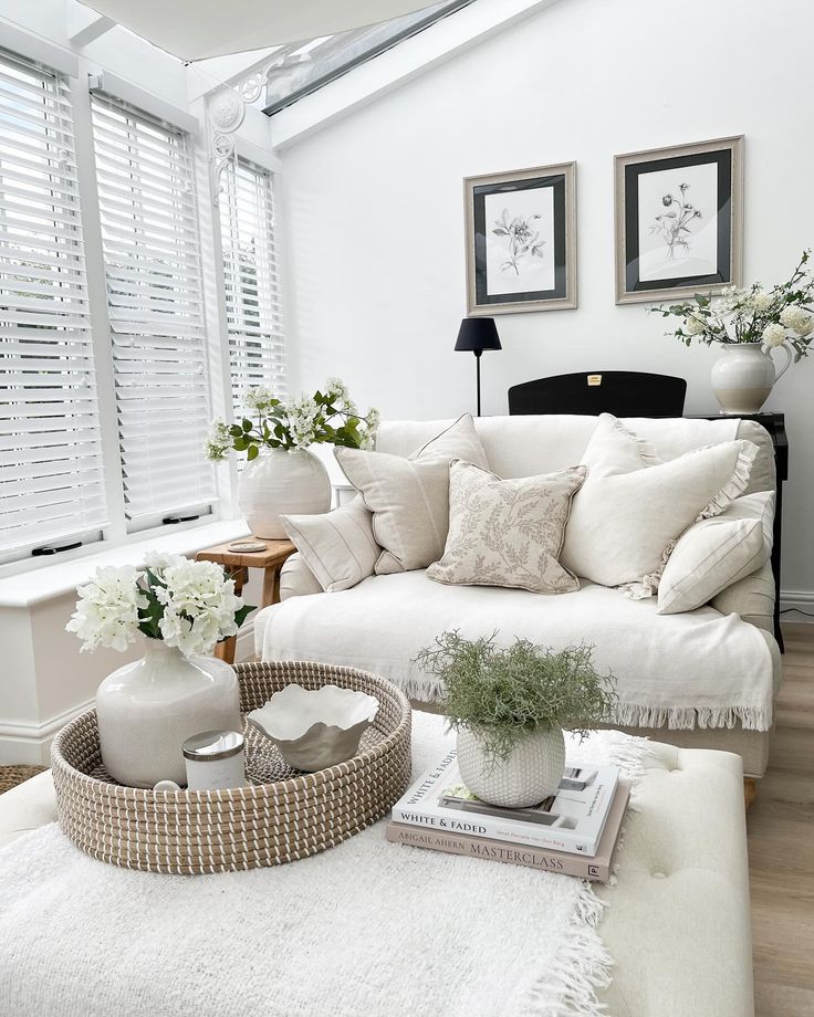 a living room filled with white furniture and flowers in vases on the coffee table