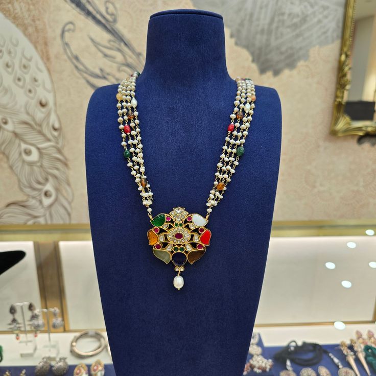 Discover the timeless elegance of our Navratan Mala. This striking piece features a prominent Navratan beads pendant paired with a luxurious four-layered chain of knotted pearls and beads. Its unique design with traditional craftsmanship making it a versatile accessory for both men and women. Length : 28 inches with 6 inch adjustable rings Material : 92.5 Hallmarked silver Stones : Natural navratan beads, natural pearls, kundans Traditional Pearl Necklace For Puja And Festivals, Traditional Pearl Necklace For Festivals And Puja, Elegant Multicolor Necklaces For Puja, Traditional Bridal Necklace With Polished Beads, Elegant Multicolor Mala For Festivals, Traditional Pearl Necklace For Puja, Traditional Kundan Necklace With Detachable Pendant For Celebrations, Traditional Temple Necklace With Pearl Pendant For Festive Occasions, Traditional Bridal Necklace With Polished Beads For Celebration