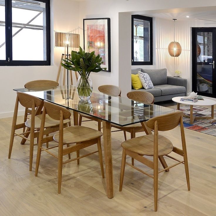 a dining room table with chairs and a couch in front of the glass top table