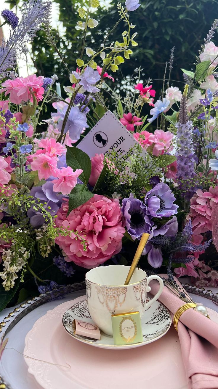 a pink plate with a cup and saucer on it next to a bouquet of flowers