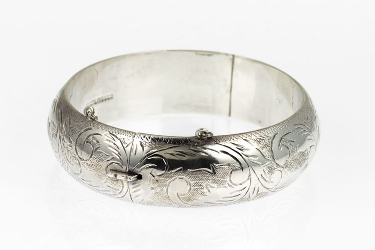 This is a hand engraved vintage sterling silver floral hinged bangle bracelet. The inside is marked Sterling 925. I've tested the piece with acid and guarantee it to be sterling silver. The bracelet is in good condition and closes securely. The outside features a hand chased floral/flower design that is crisp and detailed.  The inside of the bracelet is 2 and 1/4 of an inch long and 2 & 1/8th of an inch wide. Circumference is 6.75 inches. Outside is 5/8 of an inch wide along the band and has a t Luxury Silver Bangle With Intricate Design, Luxury Engraved Sterling Silver Bangle Bracelet, Luxury Antique Sterling Silver Bangle Bracelet, Etched Sterling Silver Bracelet For Wedding, Ornate Engraved Sterling Silver Bracelet For Anniversary, Etched Sterling Silver Bangle Bracelet For Wedding, Engraved Sterling Silver Bracelet For Wedding, Stamped Sterling Silver Bangle For Wedding, Sterling Silver Stamped Bangle For Wedding