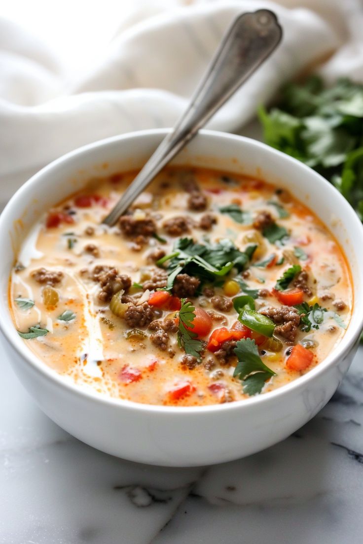 a close up of a bowl of soup on a table with a spoon in it