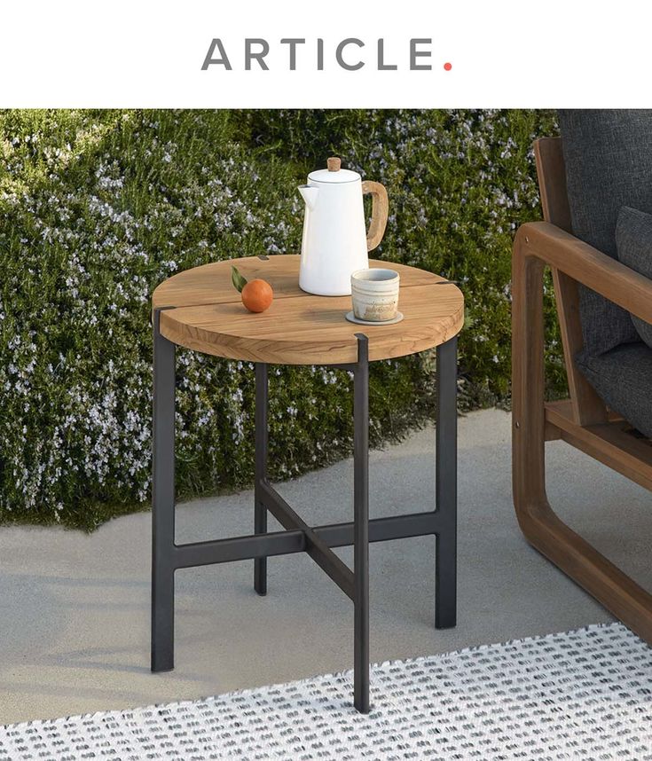 a table with an orange on it sitting next to a chair and potted plant