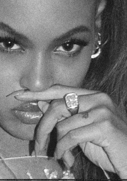 a black and white photo of a woman with her hand on her lip holding a ring