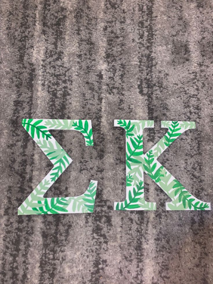 the letters k and k are made out of green leafy paper on a gray surface